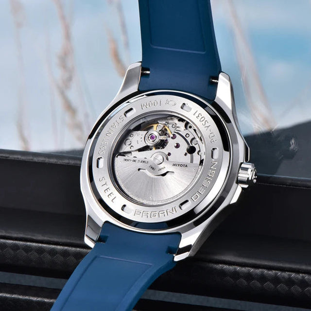 Watch with blue strap and visible mechanism on a blurred natural background