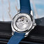 Watch with blue strap and visible mechanism on a blurred natural background